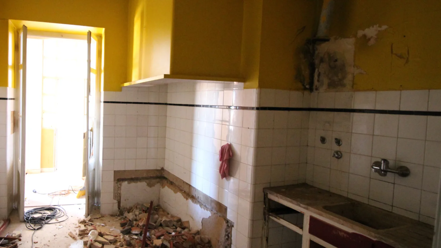 Cozinha antiga em obra de reabilitação, com azulejos e paredes por recuperar